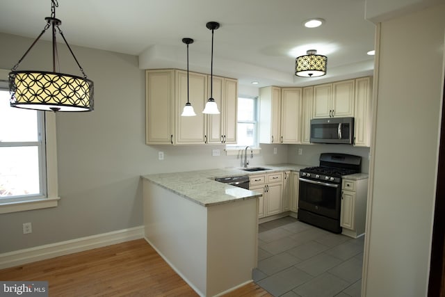 kitchen featuring pendant lighting, sink, light wood-type flooring, appliances with stainless steel finishes, and light stone counters