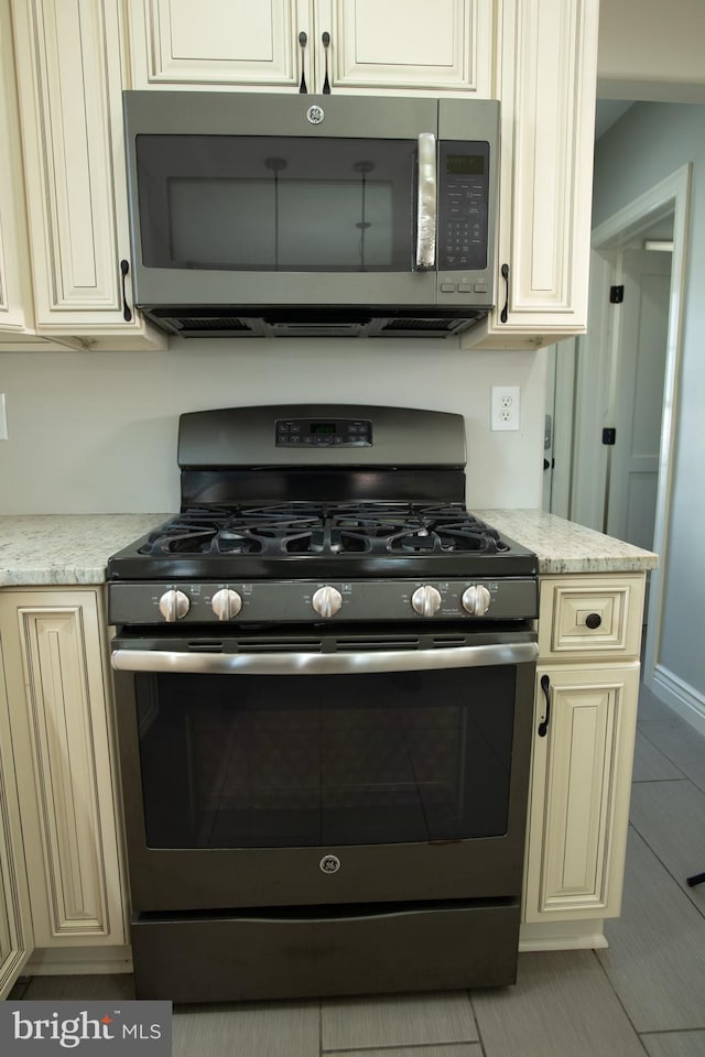 kitchen with cream cabinets, stainless steel appliances, and light tile patterned floors