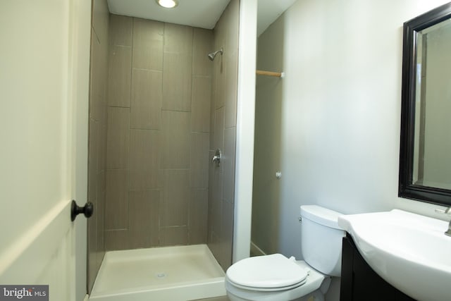 bathroom with a tile shower, vanity, and toilet