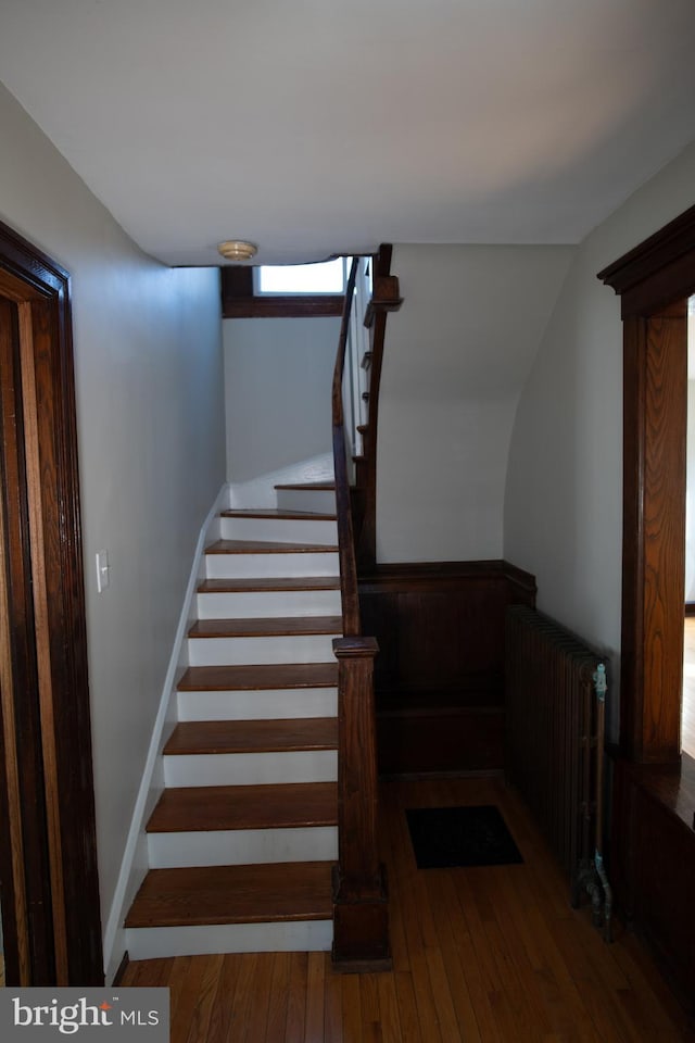 stairs featuring hardwood / wood-style floors and radiator heating unit