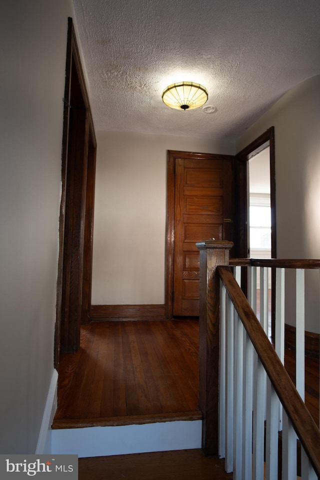 stairs featuring a textured ceiling and hardwood / wood-style flooring