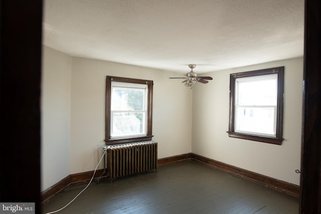 empty room featuring radiator, dark hardwood / wood-style flooring, and a healthy amount of sunlight