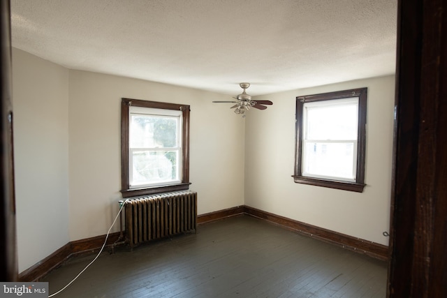 spare room featuring radiator, plenty of natural light, and dark hardwood / wood-style floors