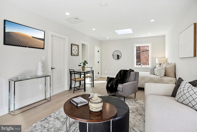 living room featuring a skylight and light hardwood / wood-style flooring