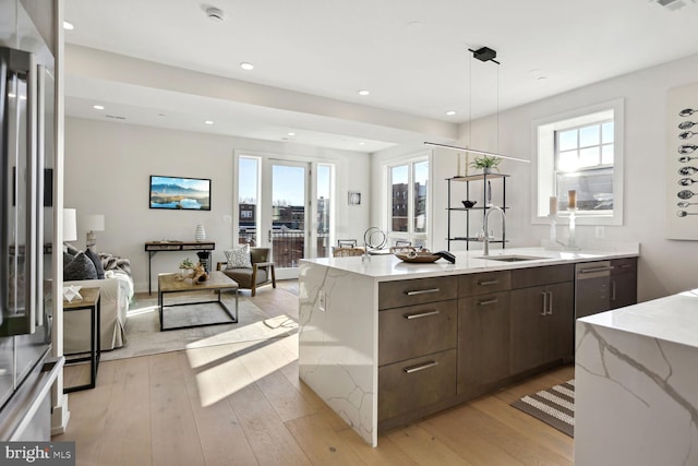 kitchen with dark brown cabinetry, sink, pendant lighting, and light wood-type flooring