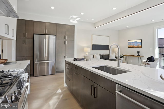 kitchen with ventilation hood, sink, light stone countertops, and stainless steel appliances