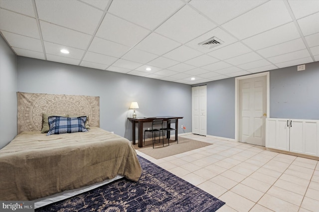 bedroom with a paneled ceiling and light tile patterned floors