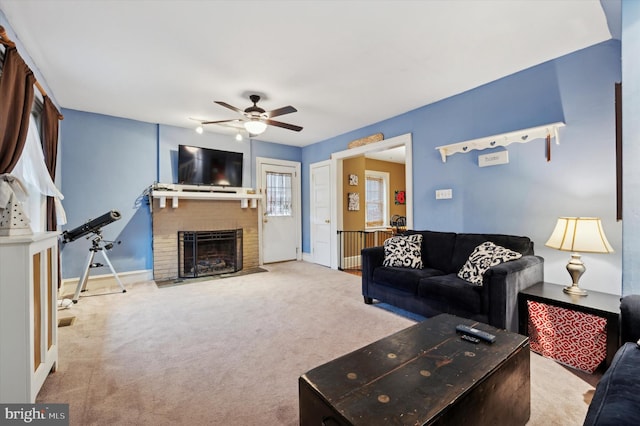 carpeted living room with ceiling fan and a fireplace