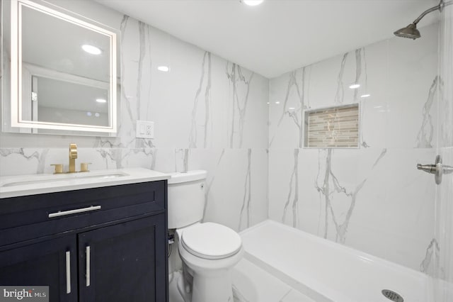 bathroom with tiled shower, vanity, toilet, and tile walls