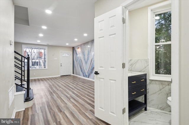 interior space featuring tile walls, a wealth of natural light, and light hardwood / wood-style flooring