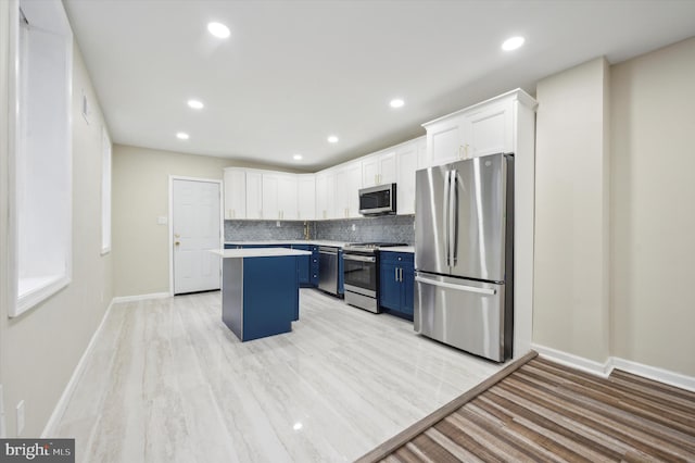 kitchen with a center island, white cabinets, light wood-type flooring, blue cabinetry, and appliances with stainless steel finishes