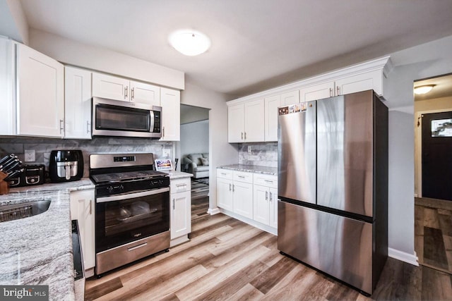 kitchen with backsplash, stainless steel appliances, and white cabinetry