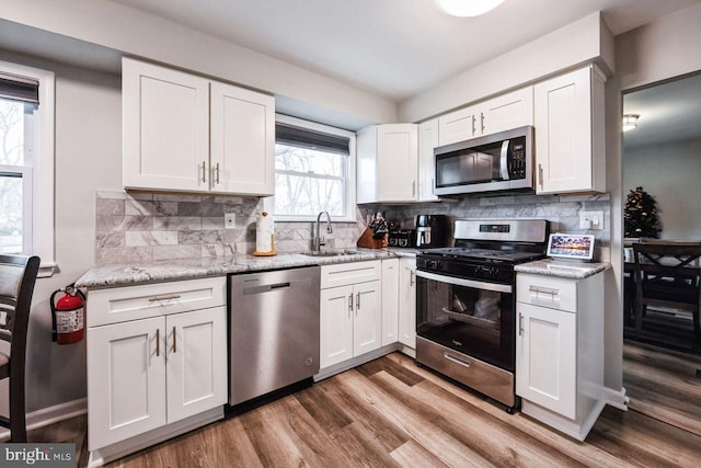 kitchen featuring tasteful backsplash, white cabinetry, light hardwood / wood-style flooring, and appliances with stainless steel finishes