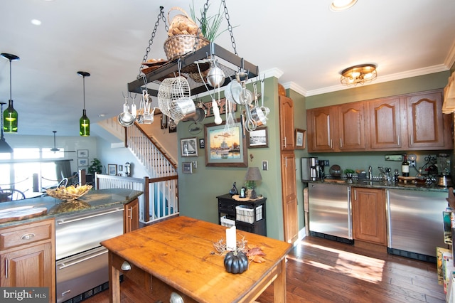 kitchen with appliances with stainless steel finishes, dark hardwood / wood-style floors, and ornamental molding