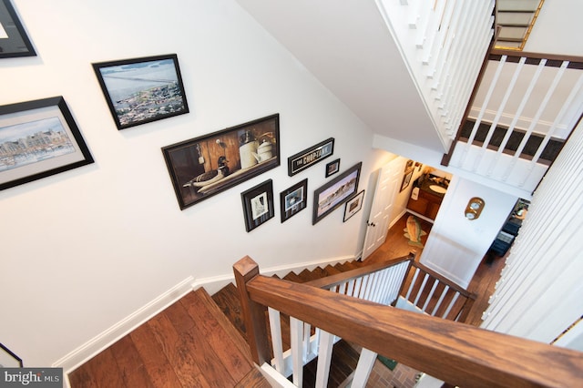 staircase featuring a towering ceiling and wood-type flooring