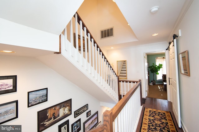 stairway featuring hardwood / wood-style floors, lofted ceiling, a barn door, and ornamental molding