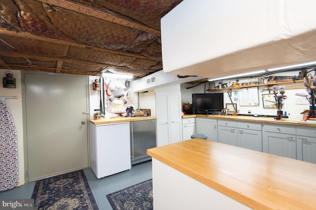 kitchen with wooden counters, stainless steel fridge, white refrigerator, and white cabinets