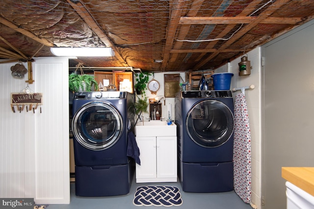 clothes washing area with cabinets and separate washer and dryer