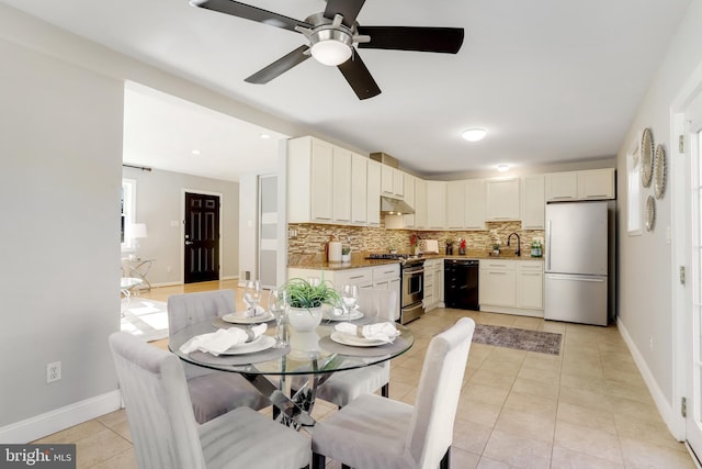 tiled dining room with ceiling fan and sink