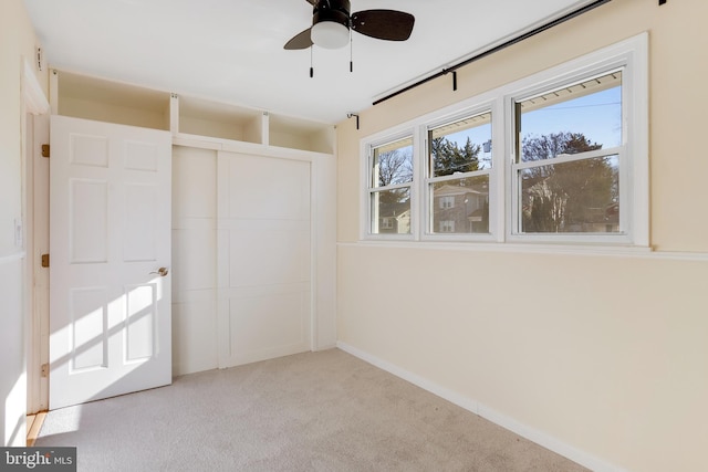 unfurnished bedroom with a closet, light colored carpet, and ceiling fan