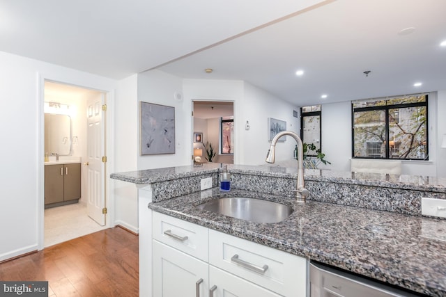 kitchen featuring dark stone countertops, white cabinetry, sink, and dishwasher