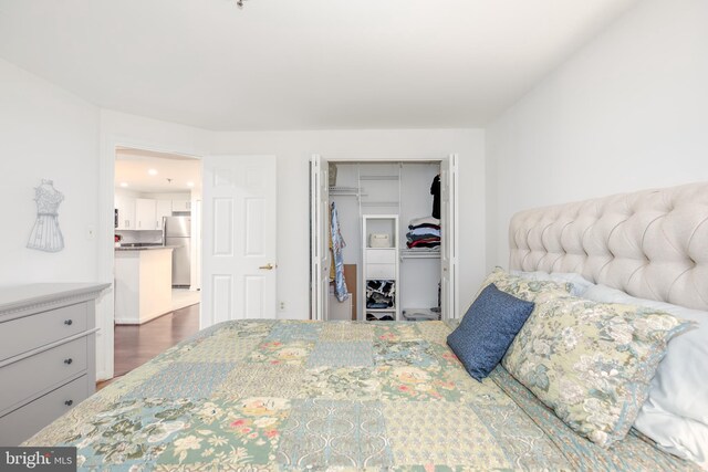 bedroom featuring dark hardwood / wood-style floors, stainless steel refrigerator, and a closet