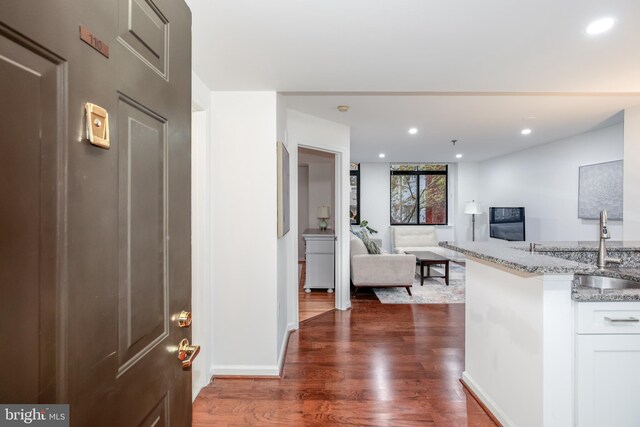 interior space with light stone countertops, dark hardwood / wood-style flooring, white cabinets, and sink