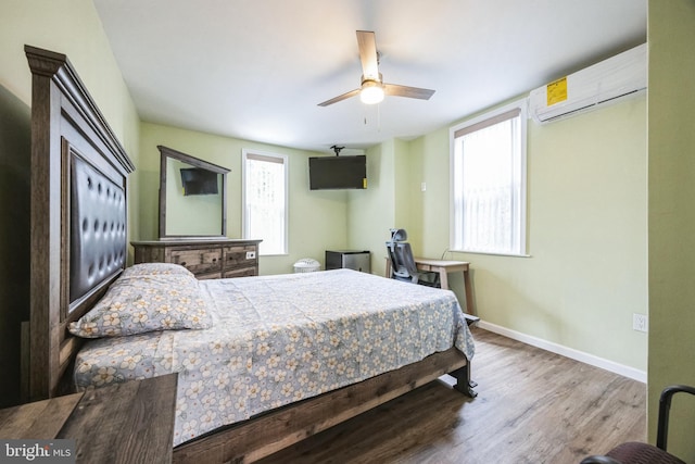 bedroom featuring an AC wall unit, multiple windows, ceiling fan, and hardwood / wood-style flooring