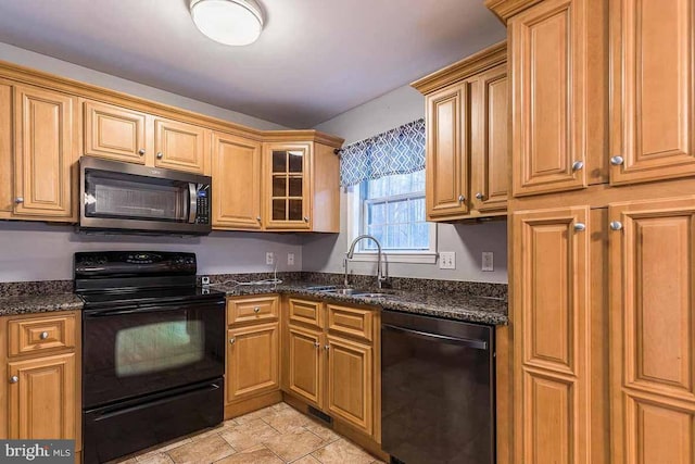 kitchen with dark stone counters, sink, and black appliances