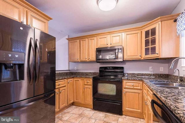 kitchen with dark stone counters, sink, and black appliances