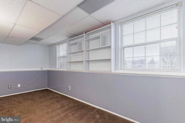 carpeted spare room featuring a drop ceiling