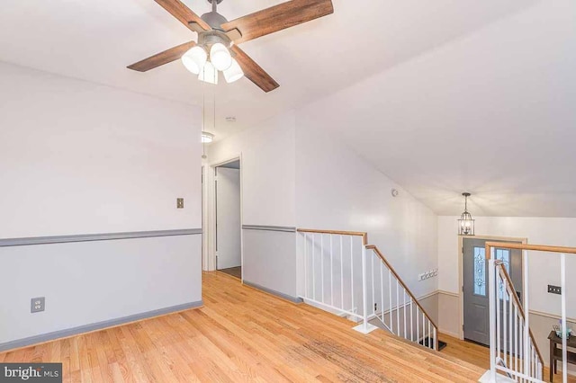 unfurnished room with ceiling fan with notable chandelier, light hardwood / wood-style flooring, and vaulted ceiling