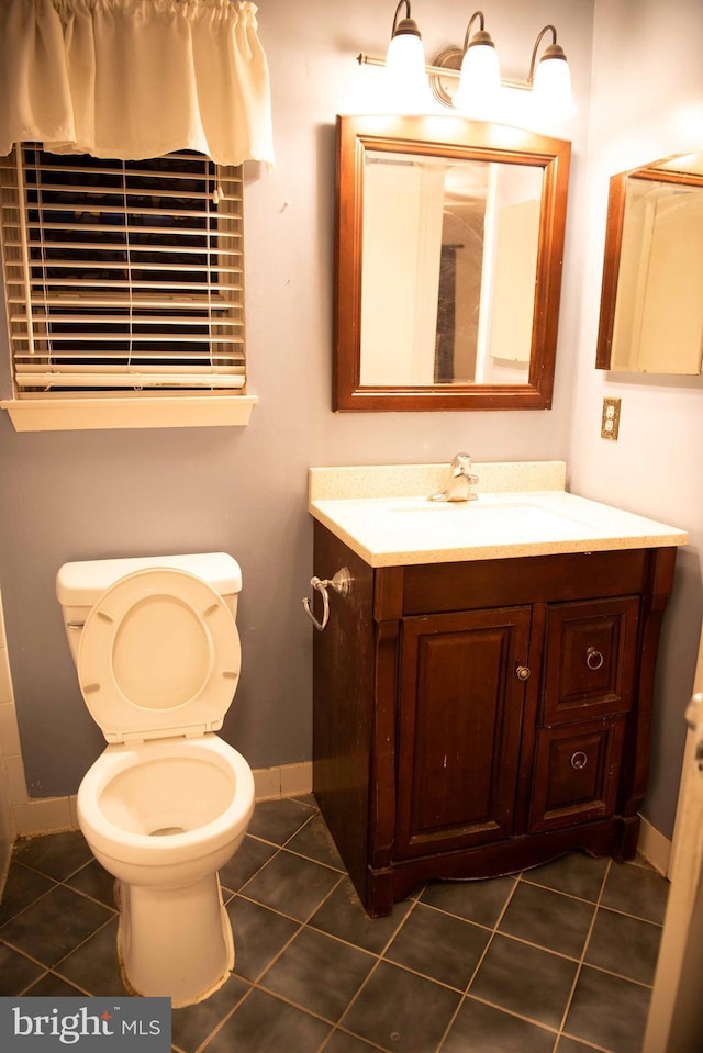 bathroom with toilet, vanity, and tile patterned floors