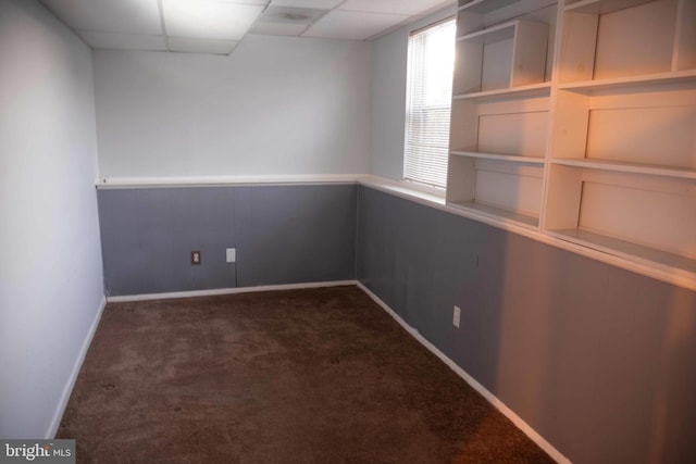 unfurnished room with a paneled ceiling and dark carpet