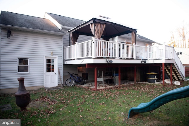 back of property featuring a playground, a lawn, and a wooden deck