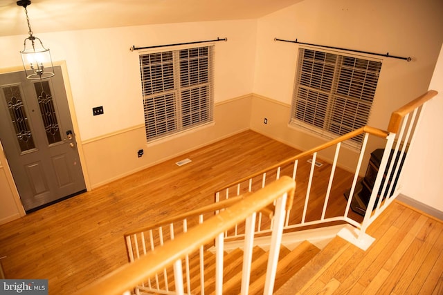 stairway with a chandelier and hardwood / wood-style flooring