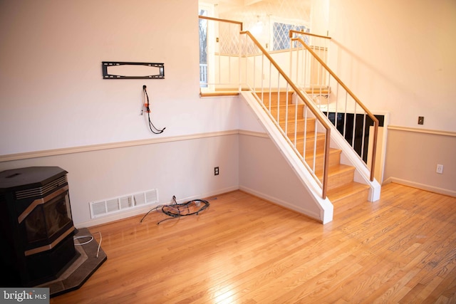 staircase featuring a wood stove and hardwood / wood-style floors