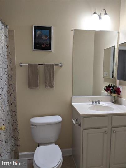 bathroom featuring vanity, curtained shower, and toilet