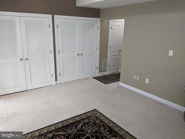 unfurnished bedroom featuring multiple closets and carpet floors