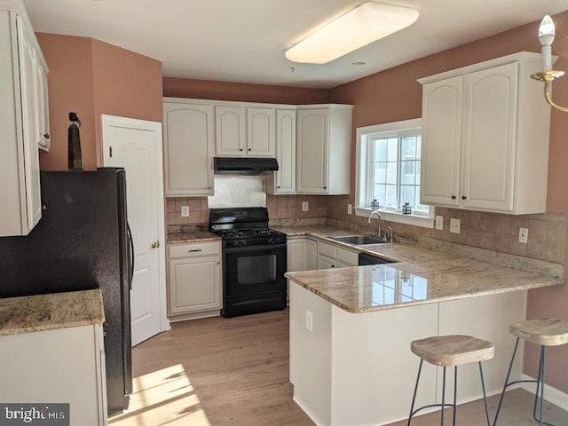 kitchen featuring white cabinetry, sink, black appliances, and kitchen peninsula