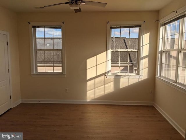 empty room with ceiling fan and dark hardwood / wood-style flooring