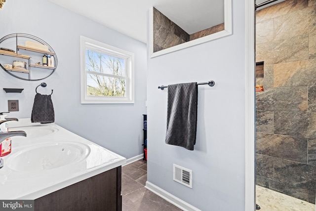 bathroom with tile patterned floors, vanity, and a tile shower