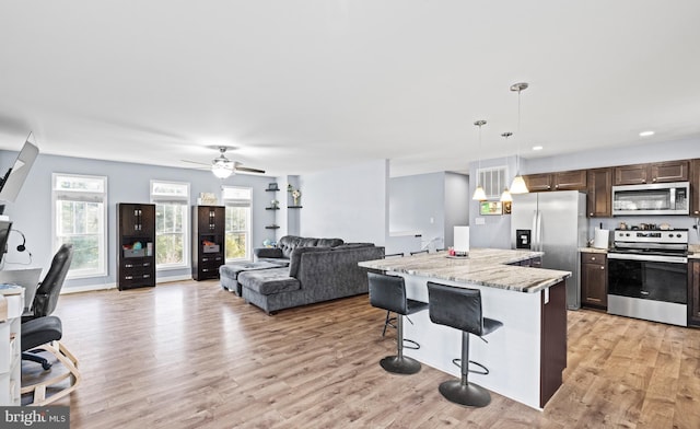 kitchen featuring pendant lighting, plenty of natural light, stainless steel appliances, and a breakfast bar