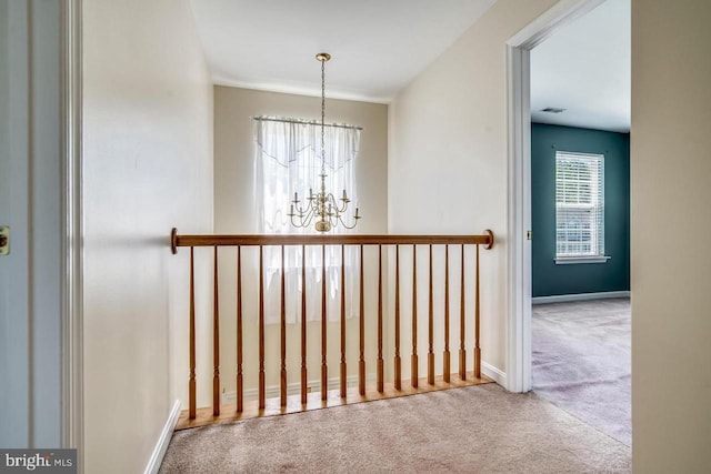 corridor with carpet and an inviting chandelier