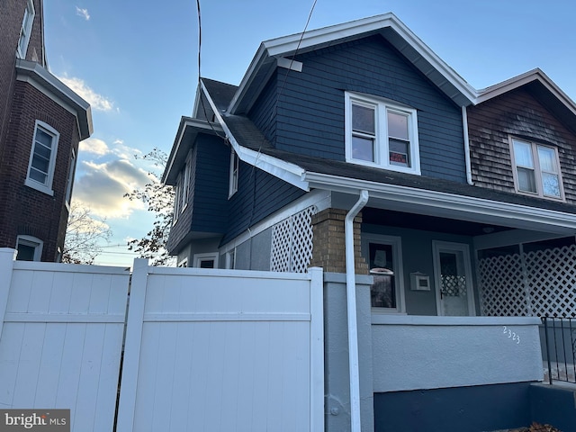 view of side of property featuring a porch and fence