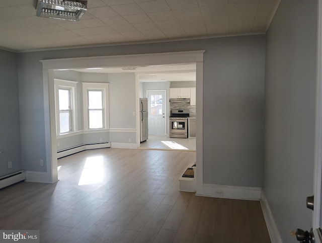 unfurnished room featuring a baseboard radiator, light hardwood / wood-style flooring, and crown molding