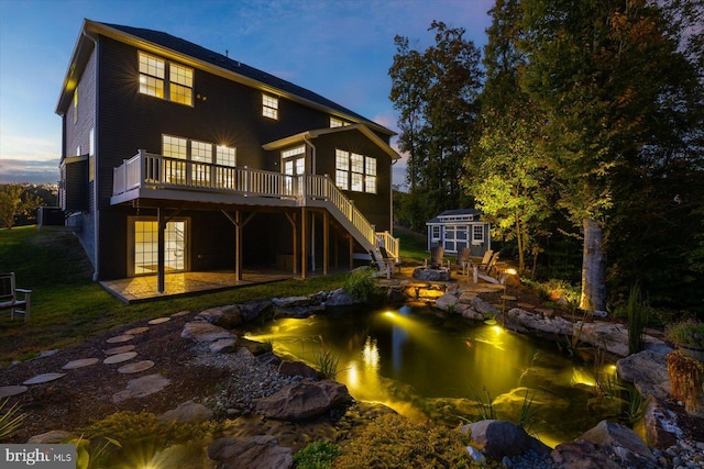 back house at dusk with a fire pit, central AC, a wooden deck, and french doors