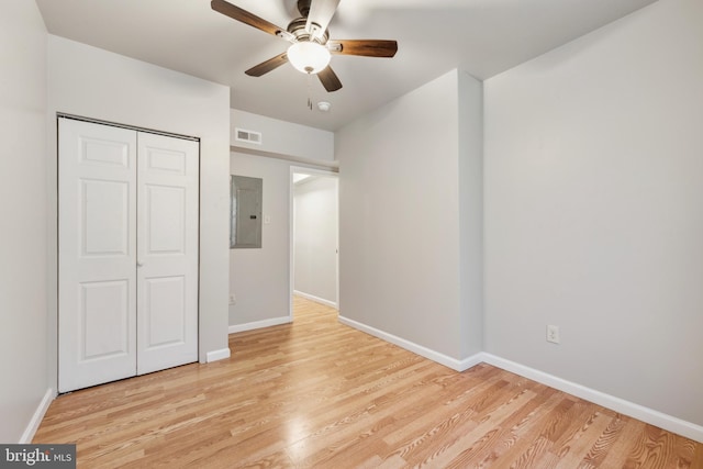 unfurnished bedroom with a closet, electric panel, light hardwood / wood-style floors, and ceiling fan