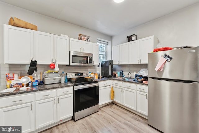 kitchen featuring backsplash, white cabinetry, stainless steel appliances, and light hardwood / wood-style flooring