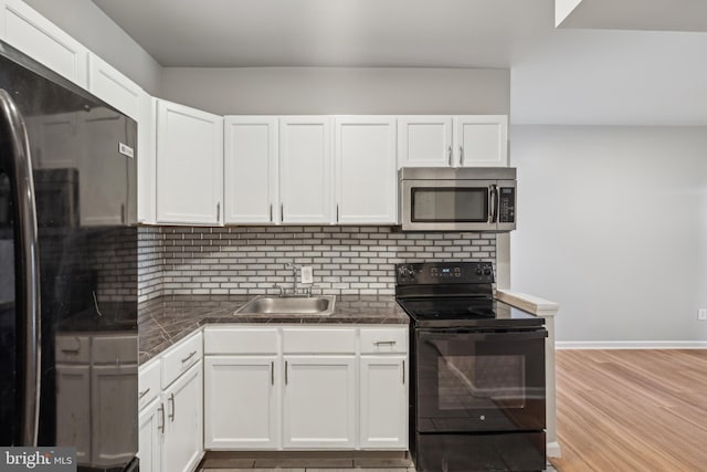 kitchen with black appliances, sink, decorative backsplash, light wood-type flooring, and white cabinetry